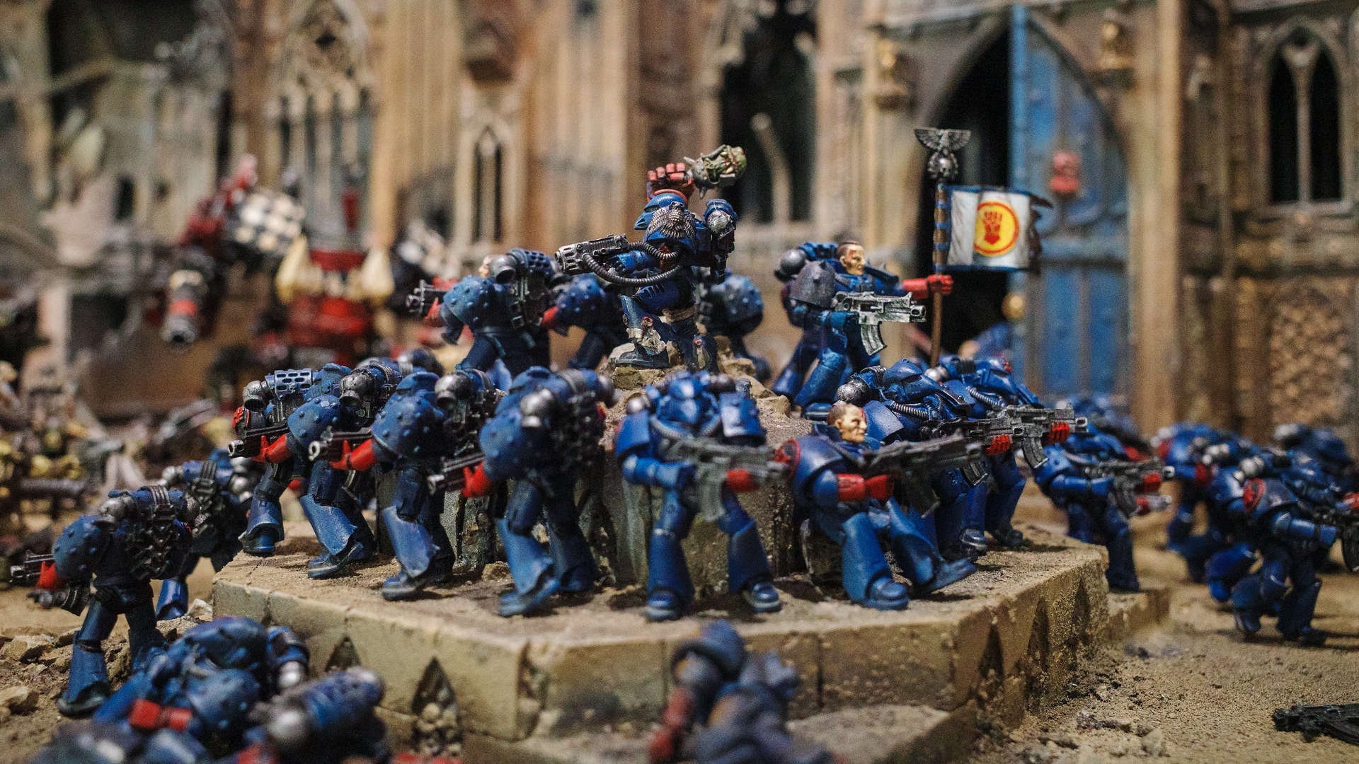 Games Workshop's Warhammer World diorama of Crimson Fists models standing on Rynn's World, banner raised, commander with an Ork head held high